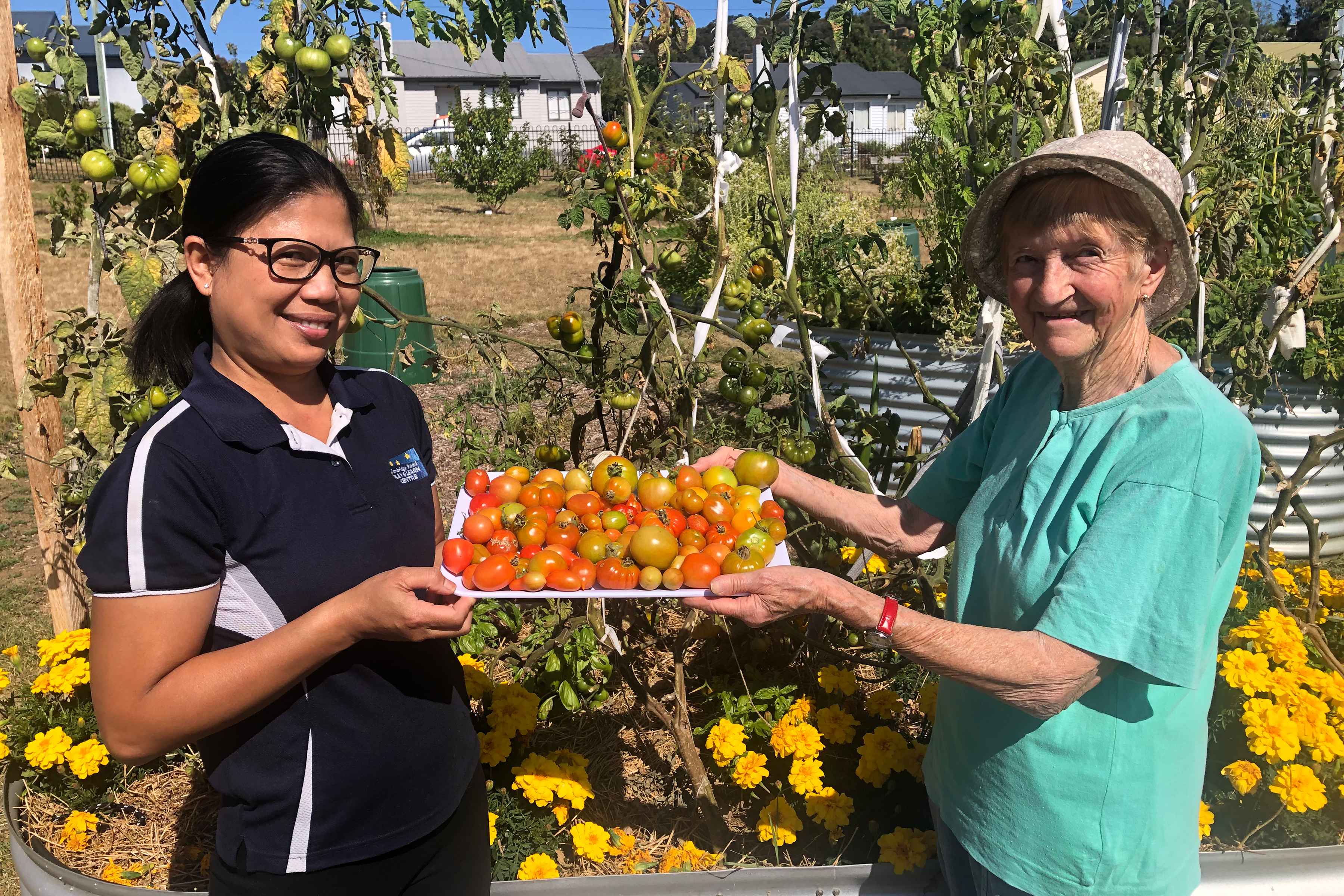 Climate action champions Lily Winzil and Marie Boden with their tomato harvest at the Warrane Community Garden.
